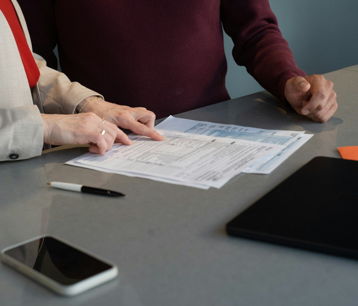 Deux personnes examinent un dossier posé sur une table de travail